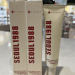 K-Secret Seoul 1988 Eye Cream 30ml tube displayed next to two product boxes on a store counter with blurred shelves in the background.