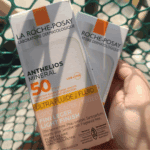 Hand holding La Roche-Posay Anthelios Mineral Tinted Ultra Fluid SPF 50 sunscreen boxes for sensitive skin