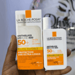 Hand holding La Roche Posay Anthelios UVMune 400 SPF 50 plus invisible fluid sunscreen with packaging box, ultra long UVA protection lightweight sunscreen for daily use.