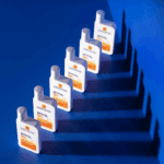 Multiple La Roche Posay Anthelios UVMune 400 SPF 50 plus sunscreen bottles arranged in a row on blue background, ultra long UVA protection lightweight invisible fluid sunscreen.
