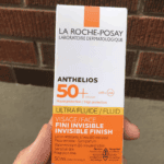 Hand holding La Roche-Posay Anthelios Ultra Fluid SPF 50+ invisible finish face sunscreen box for sensitive skin