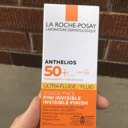 Hand holding La Roche-Posay Anthelios Ultra Fluid SPF 50+ invisible finish face sunscreen box for sensitive skin