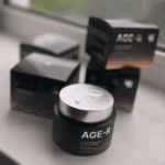 Jar of Medicube AGE-R Glutathione Glow Capsule Cream with a silver lid and a small drop of cream on top, placed on a surface with several AGE-R product boxes in the background.