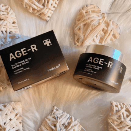 Medicube AGE-R Glutathione Glow Capsule Cream jar and product box placed on a soft textured surface with woven heart decorations around them.