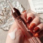 Hand holding Medicube Collagen Glow Booster Serum 15ml bottle with serum dropper and product texture on the skin.