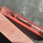 Medicube Collagen Glow Booster Serum 15ml bottle placed next to its box packaging on a textured dark surface.