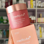 Hand holding Medicube Collagen Jelly Cream with product box in front of skincare shelf.
