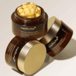 Medicube Deep Vita C Capsule Cream jars with gold lids, one open showing vitamin C capsules in gel inside the moisturizer.