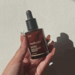 Hand holding Medicube Glutathione Glow Serum brightening serum bottle with dropper.