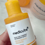 Hand holding Medicube Kojic Acid Turmeric Niacinamide Serum 30ml yellow dropper bottle with 1% kojic acid, turmeric, and 5% niacinamide for brightening and improving skin tone.