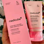 Hand holding Medicube PDRN Pink Caffeine Night Wrapping Mask 75ml tube and pink product box with PDRN, caffeine, and niacinamide for overnight soothing and revitalizing skincare.