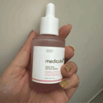 Hand holding Medicube PDRN Pink Peptide Serum 30ml collagen peptide skincare serum bottle.