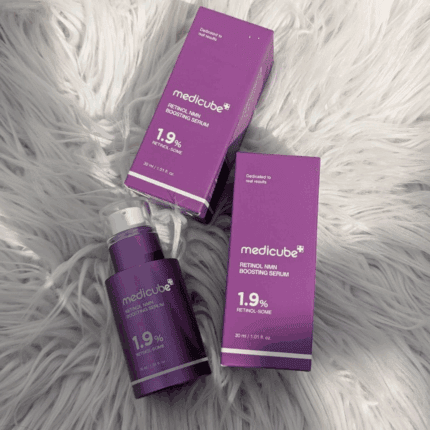 Medicube Retinol NMN Boosting Serum 1.9% bottle and two purple product boxes placed on a white faux fur surface.