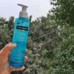 Hand holding Neutrogena Hydro Boost Water Gel Cleanser with hyaluronic acid outdoors, hydrating face wash that boosts hydration and leaves skin refreshed and soft.