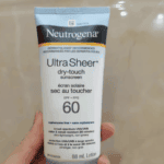 Hand holding Neutrogena Ultra Sheer Dry-Touch Sunscreen SPF 60 88ml bottle lightweight non-greasy broad spectrum UVA UVB protection