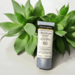 Neutrogena Ultra Sheer Dry-Touch Sunscreen SPF 60 88ml tube placed in front of green succulent plant on white background natural skincare concept