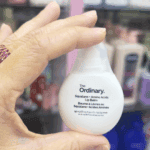 Hand holding The Ordinary Squalane + Amino Acids Lip Balm 15ml hydrating lip balm